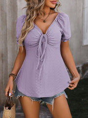 a woman wearing a purple top and denim shorts