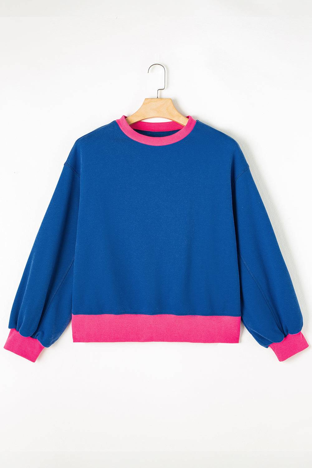 a blue sweatshirt with pink trims hanging on a hanger