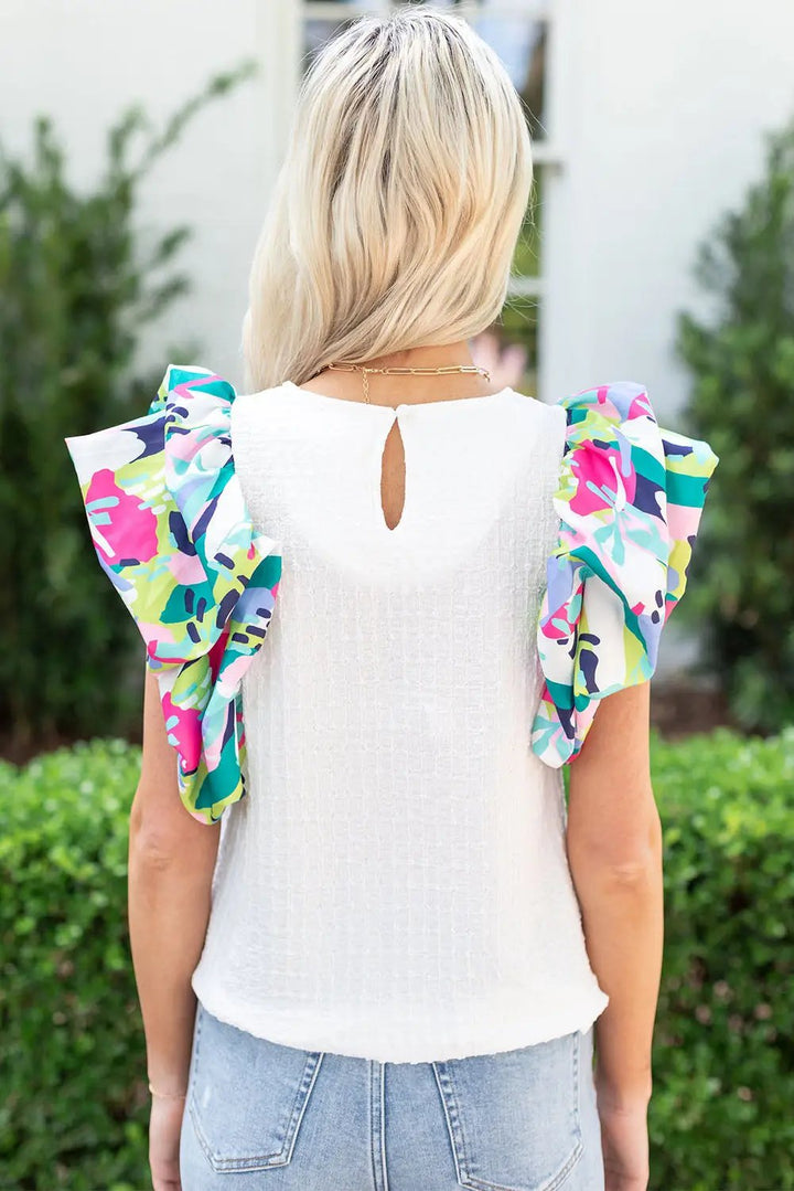 a woman wearing a white top with floral sleeves