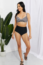 a woman in a leopard print bikini top and black high waisted shorts