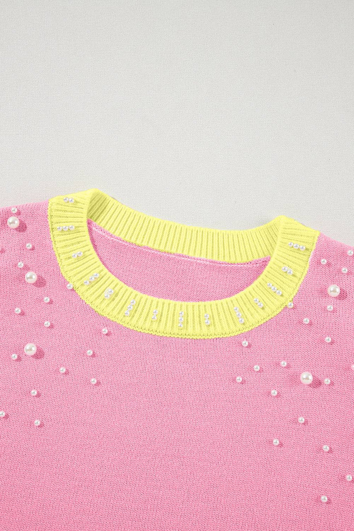 a pink sweater with yellow trim and white flowers