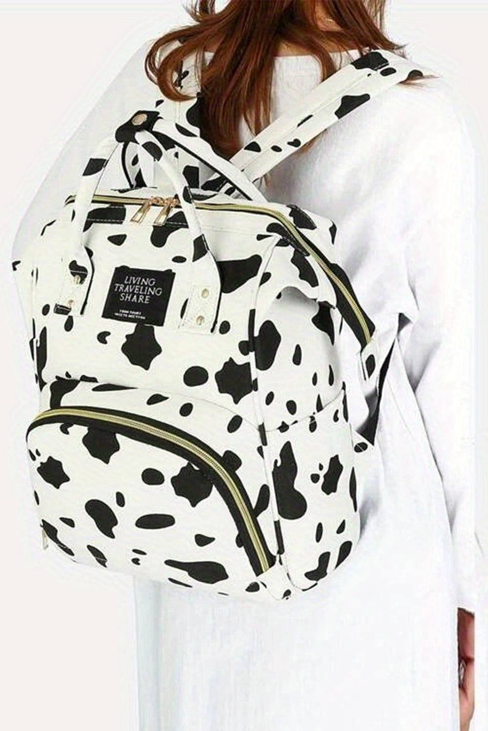 a woman wearing a black and white cow print backpack