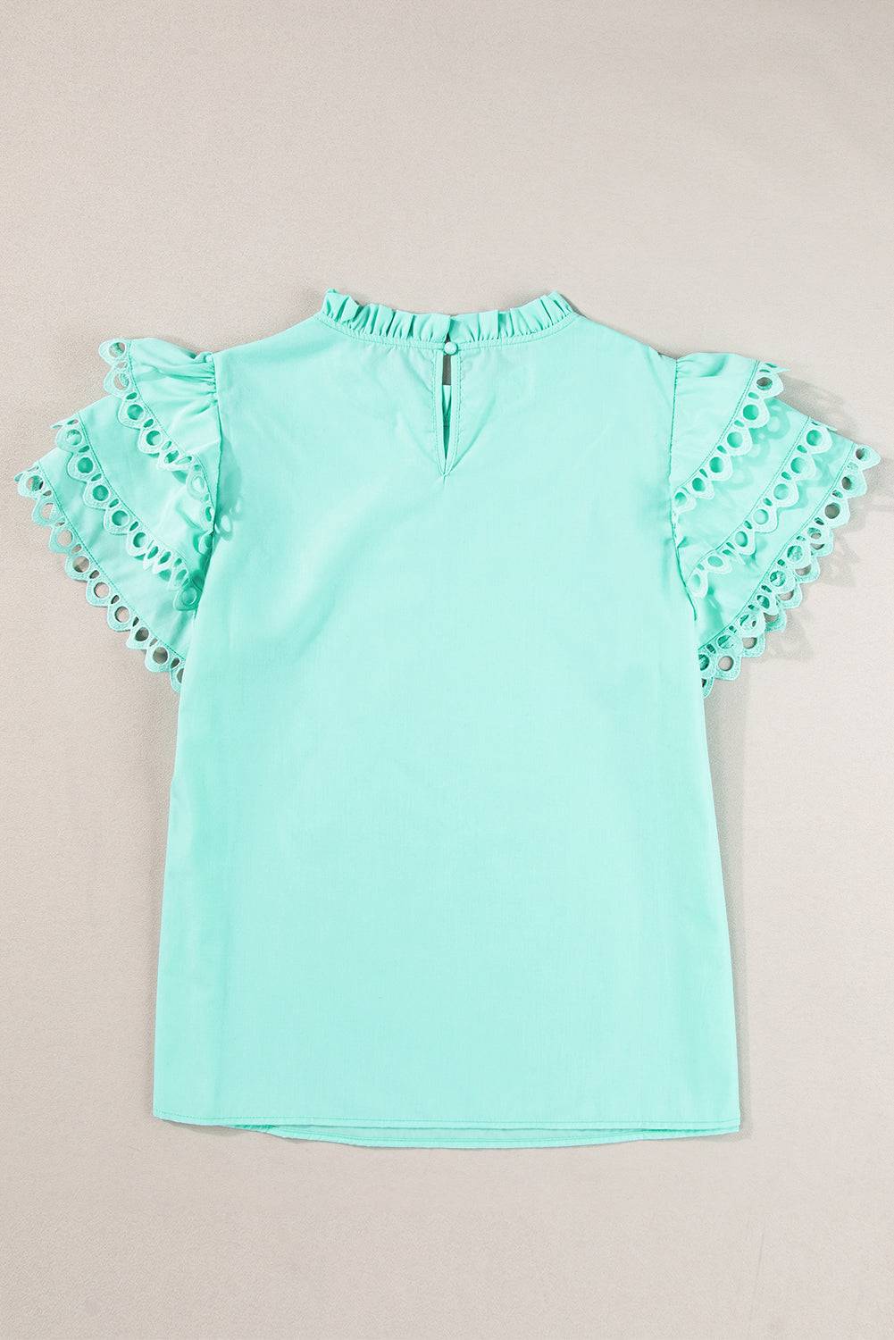 a green top with ruffles on the sleeves