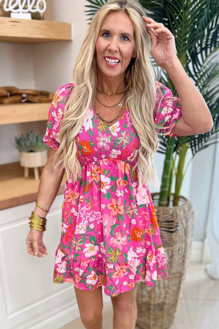 a woman in a pink floral dress posing for a picture