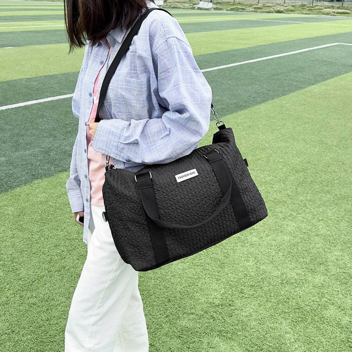 a woman carrying a black bag on a field