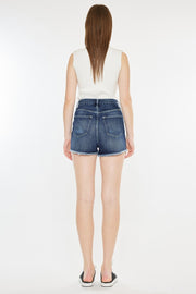 the back of a woman in a white top and denim shorts