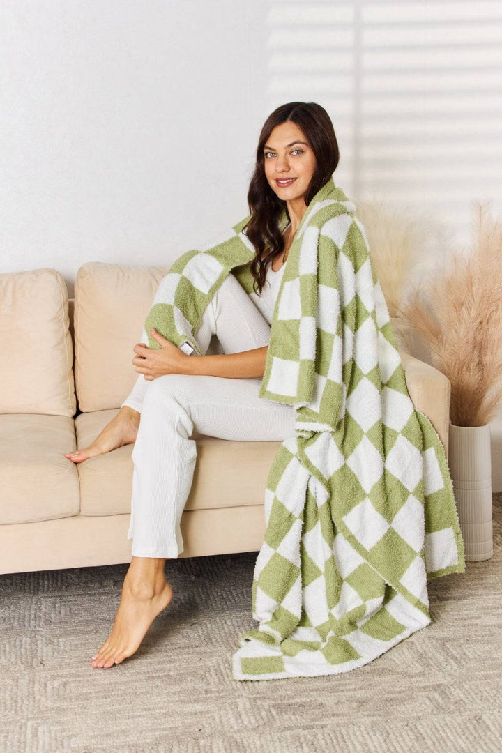 a woman sitting on a couch wearing a green and white checkered blanket