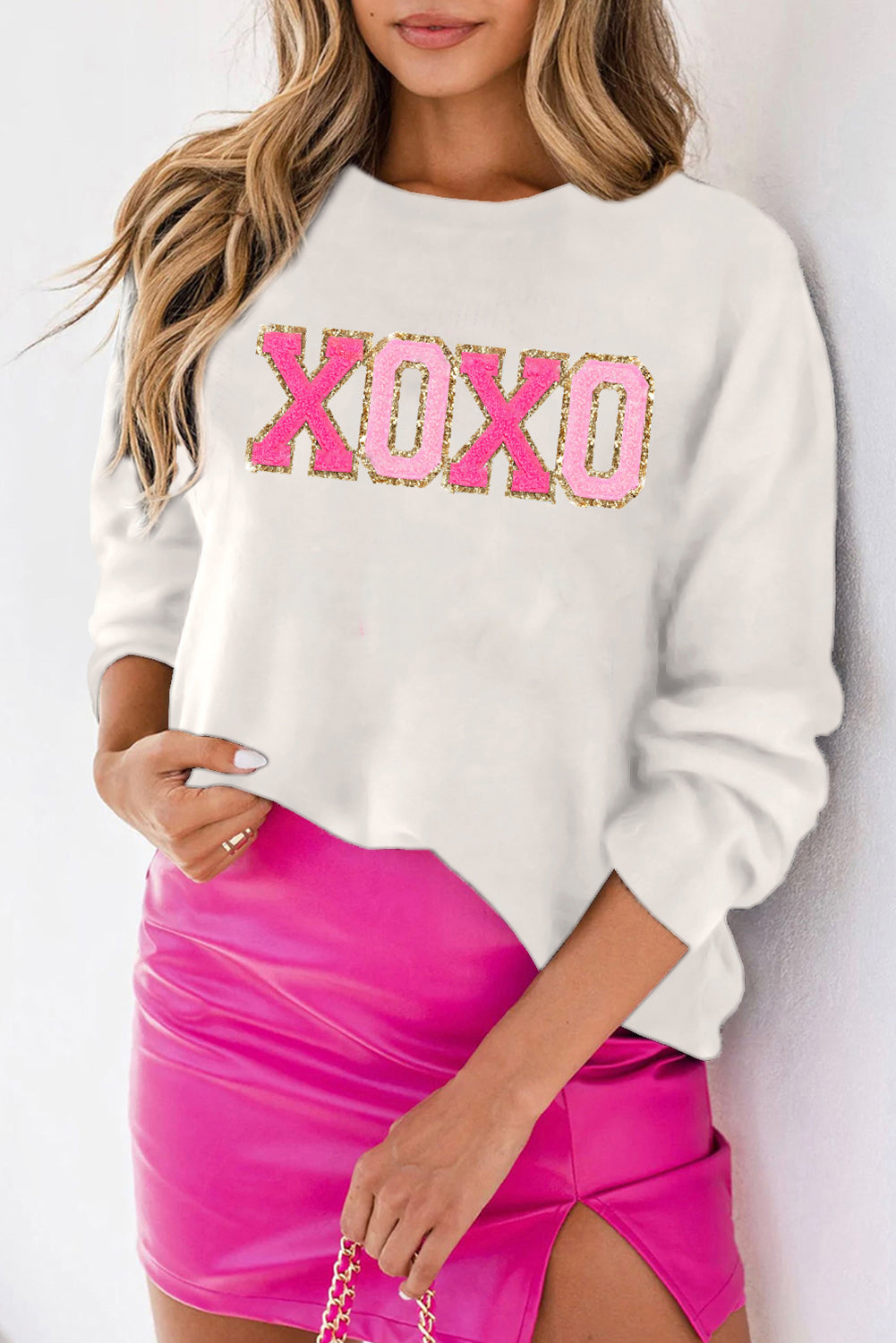 a woman wearing a white sweatshirt and pink skirt