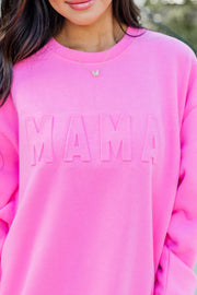 a woman wearing a pink sweatshirt with the word mama printed on it