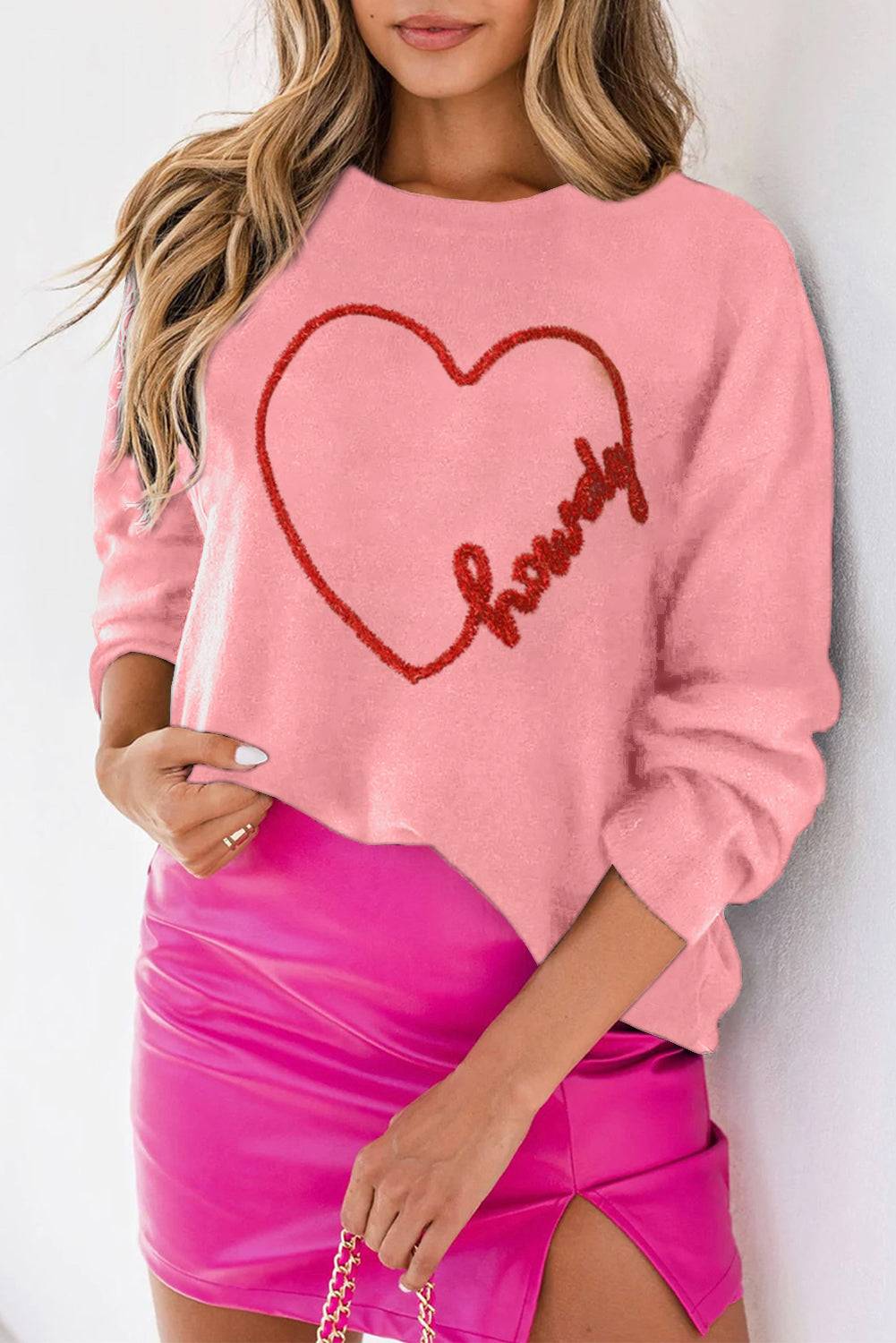 a woman wearing a pink sweater with a heart drawn on it