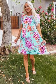 a woman standing in the grass wearing a blue floral dress