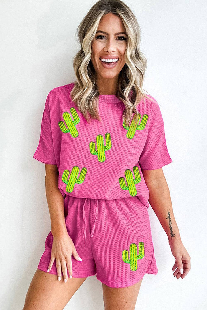 a woman wearing a pink outfit with green cactus designs on it
