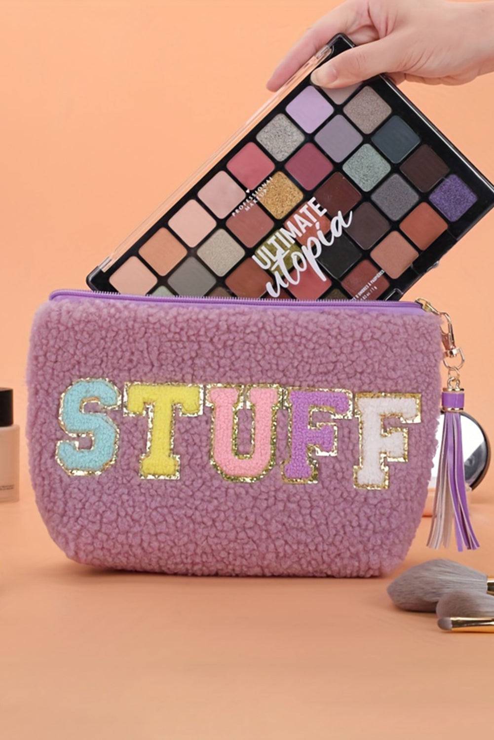 a person is holding a makeup bag with the word stuff on it