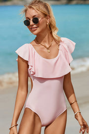 a woman in a pink one piece swimsuit on the beach