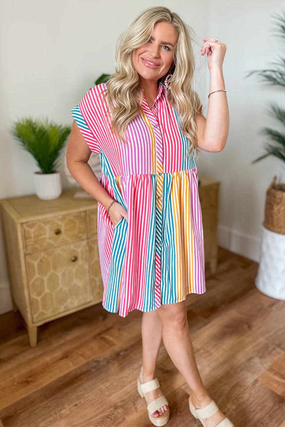 a woman posing in a colorful striped dress