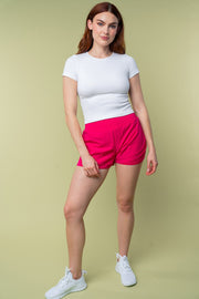 a woman in a white shirt and pink shorts