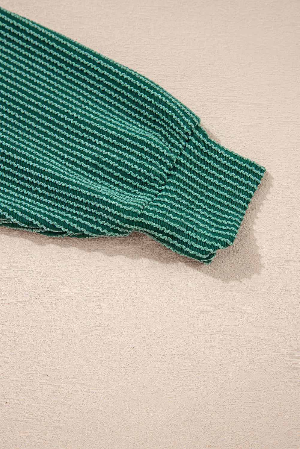 Sleeve cuff detail of green Evergreen JOLLY Corded Top. Ribbed texture adds style and warmth from Faith & Co. Boutique.
