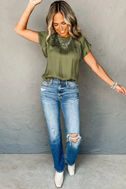 a woman wearing ripped jeans and a green top