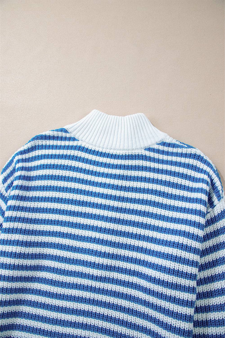 a blue and white striped sweater hanging on a wall