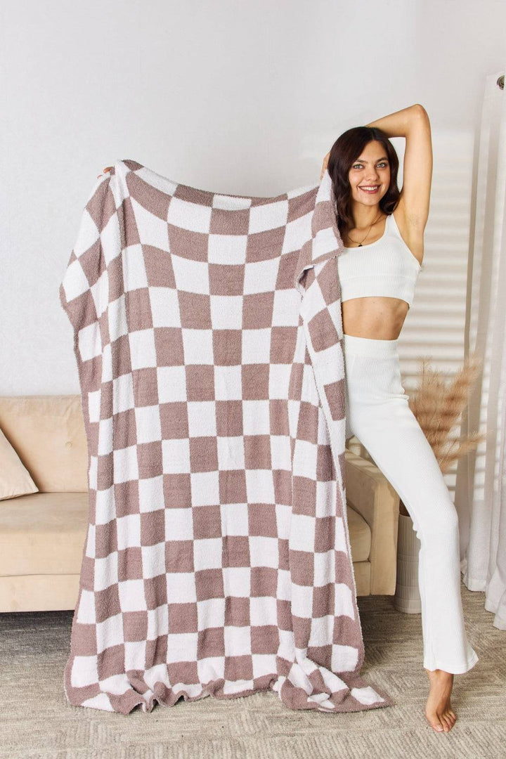 a woman holding up a checkered blanket in a living room