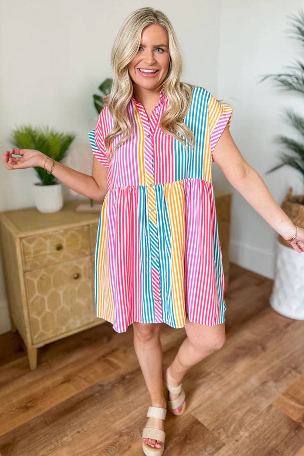 a woman standing in a room wearing a colorful striped dress