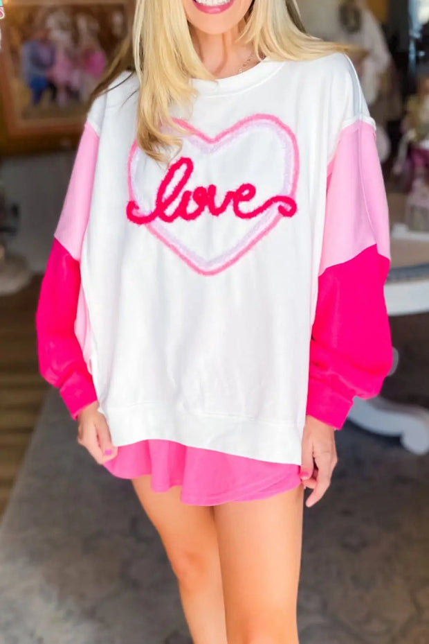 a blonde woman wearing a white and pink shirt with the word love on it