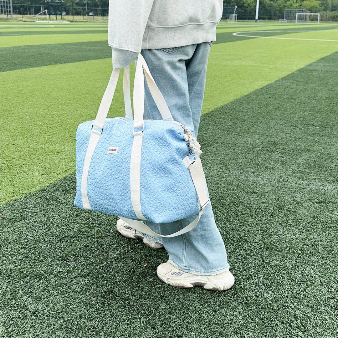 a person standing on a field with a blue bag