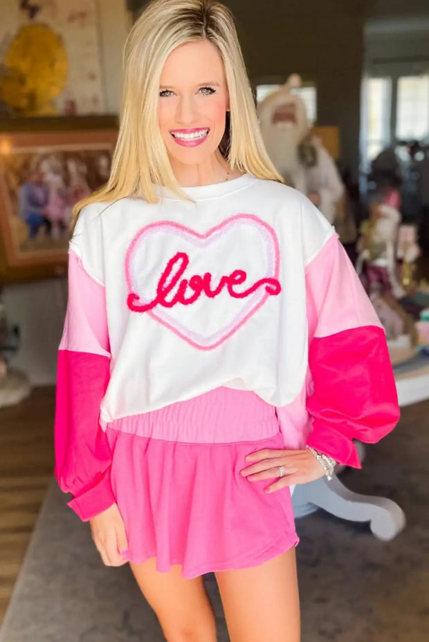 a woman wearing a pink and white sweater with a heart on it