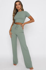 a woman wearing a green crop top and wide legged pants