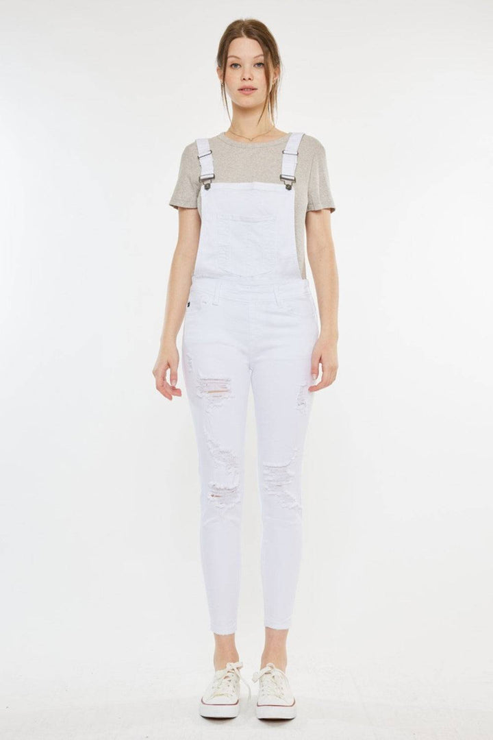 a woman wearing white overalls and a t - shirt