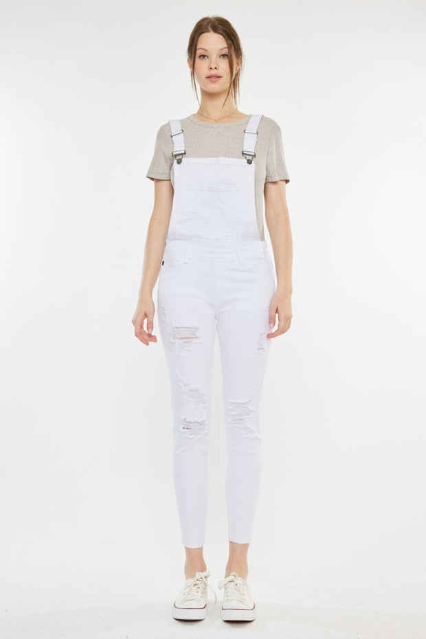 a woman wearing white overalls and a t - shirt