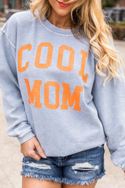 a woman wearing a sweater that says cool mom