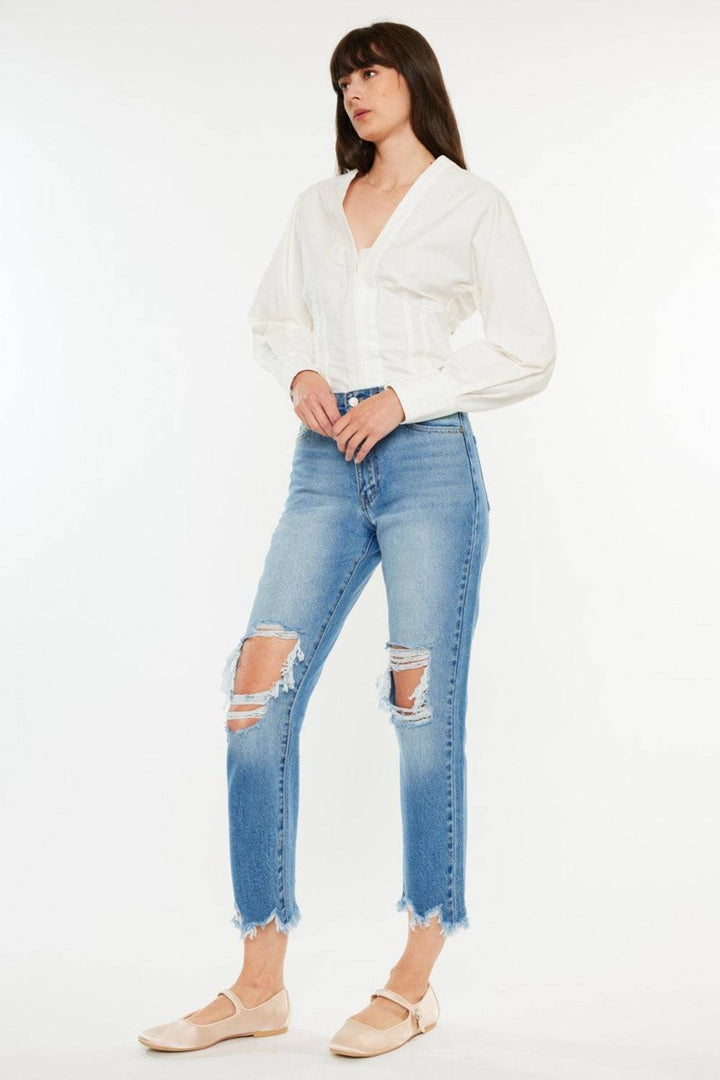 a woman wearing a white blouse and ripped jeans