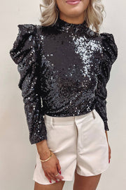 a woman wearing a black sequin top and white shorts