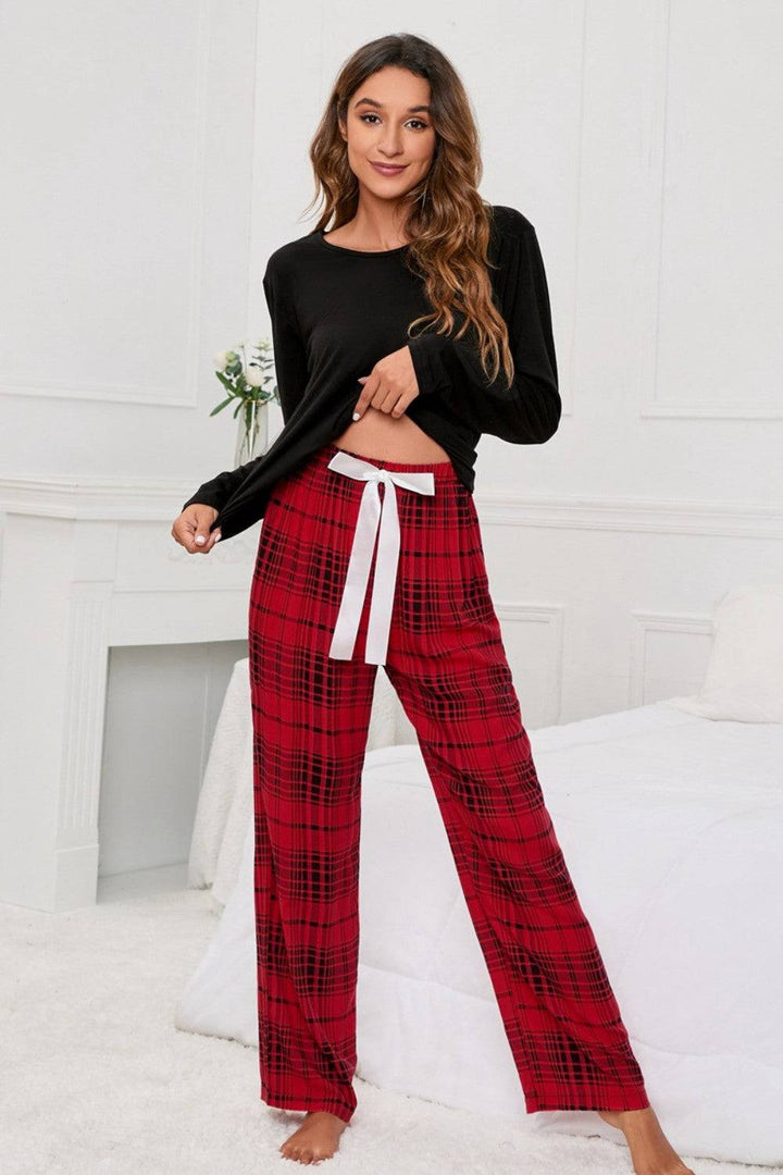 a woman in a black top and red plaid pants