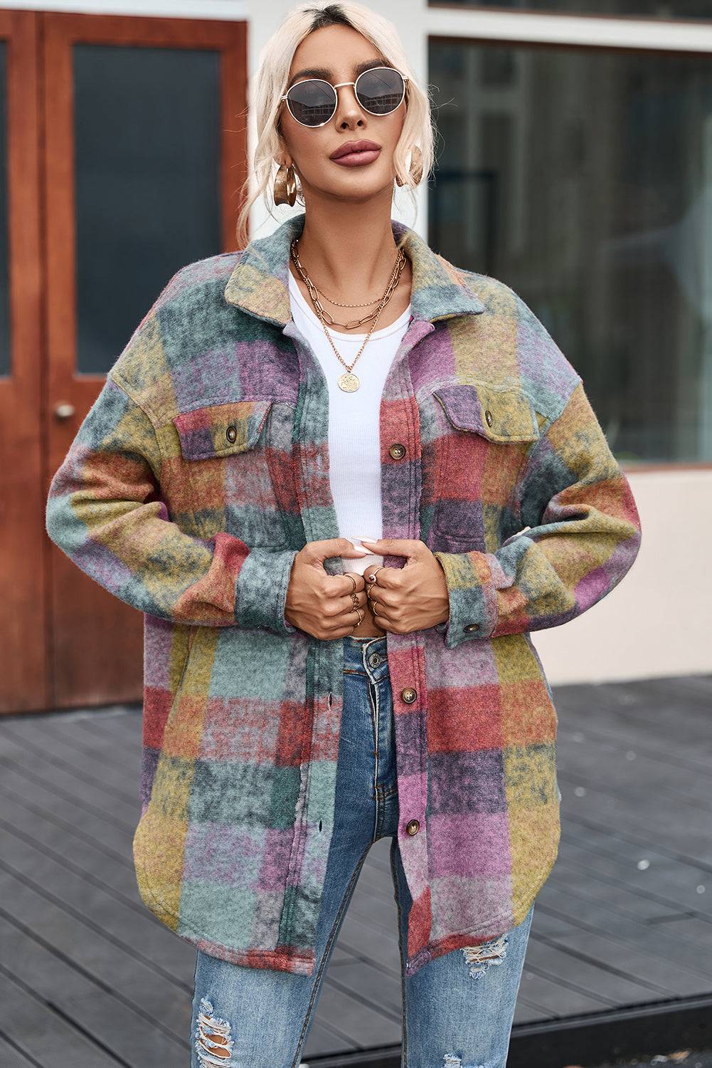 a woman wearing a multicolored jacket and ripped jeans