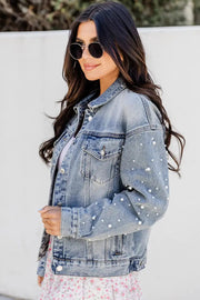 a woman wearing a denim jacket and floral skirt