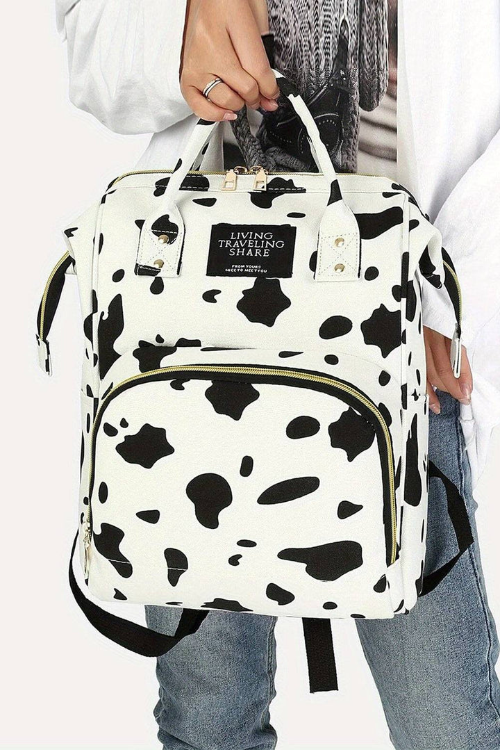 a woman is holding a cow print backpack