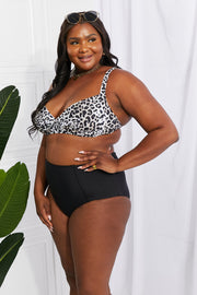 a woman in a leopard print bikini top and black shorts