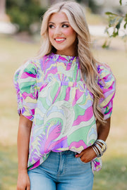a woman with blonde hair wearing a colorful top