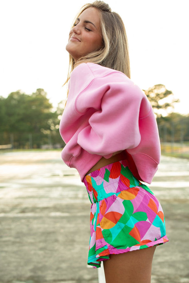 a woman wearing a pink sweater and colorful shorts