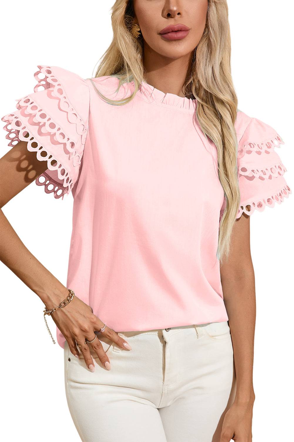 a woman wearing a pink top with scalloped sleeves