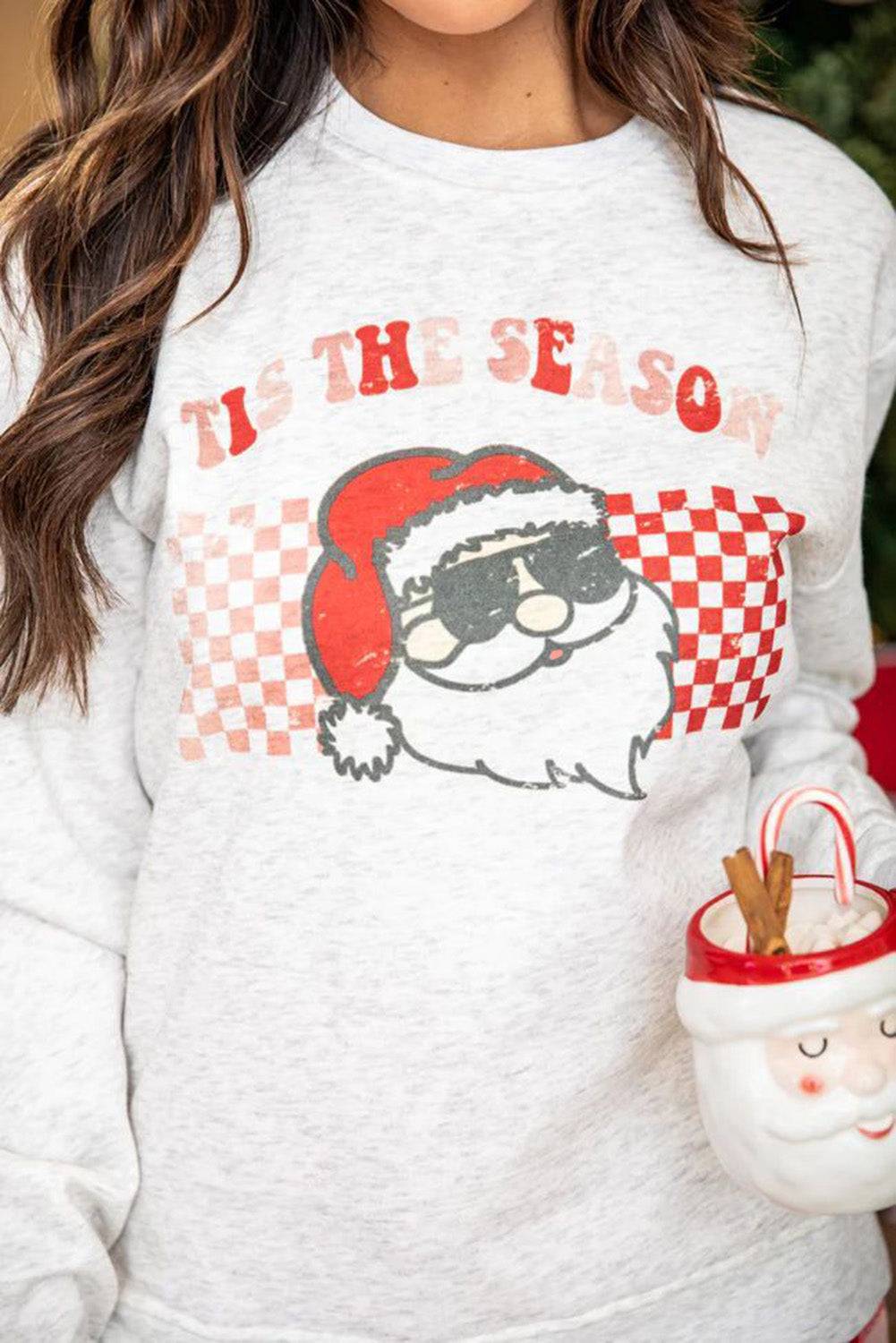 a woman wearing a santa clause sweatshirt holding a candy cane