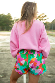 a woman in a pink sweater and colorful shorts