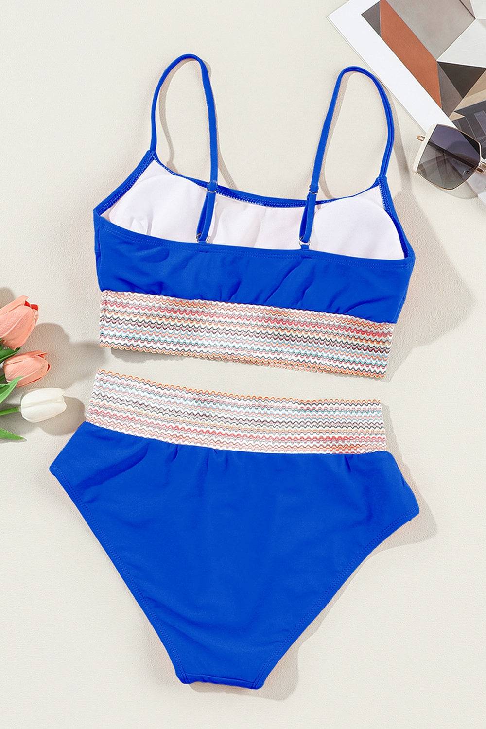 a blue and white one piece swimsuit next to a flower