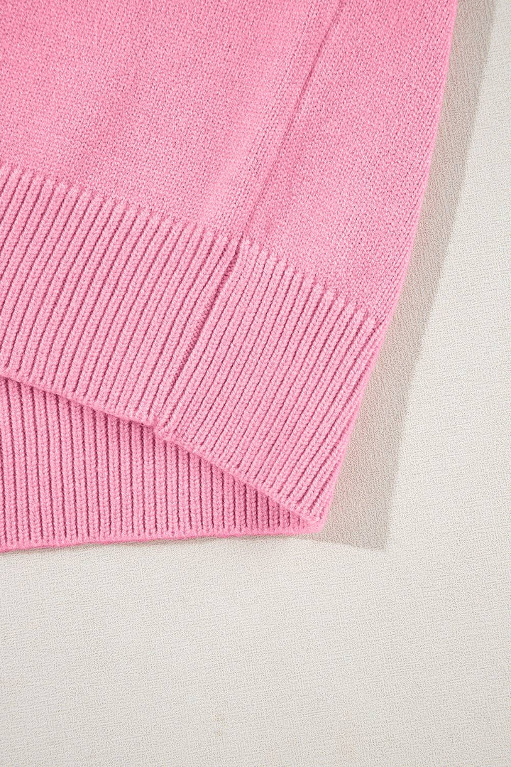 a pink sweater laying on top of a white surface