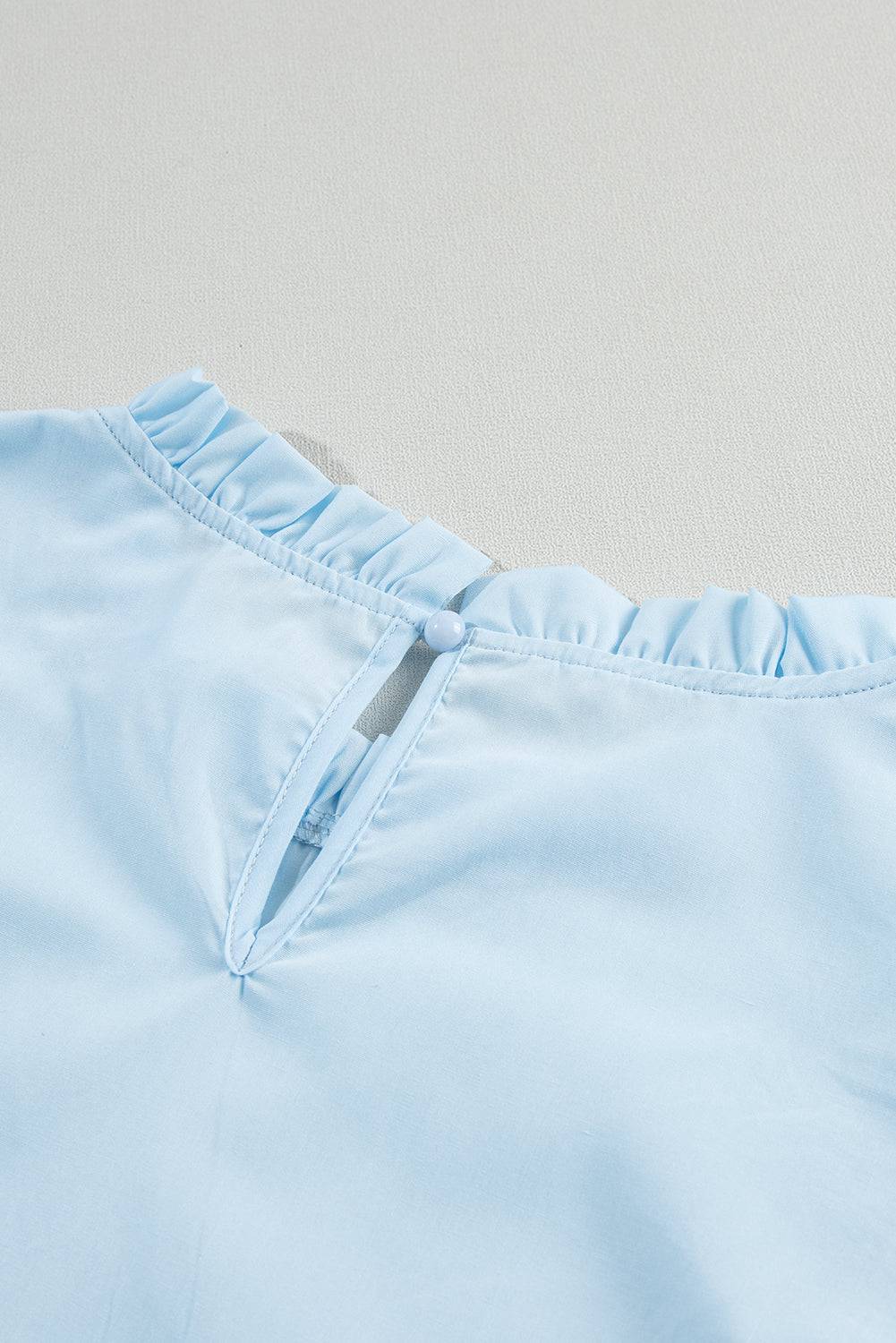 a close up of a light blue shirt on a white surface