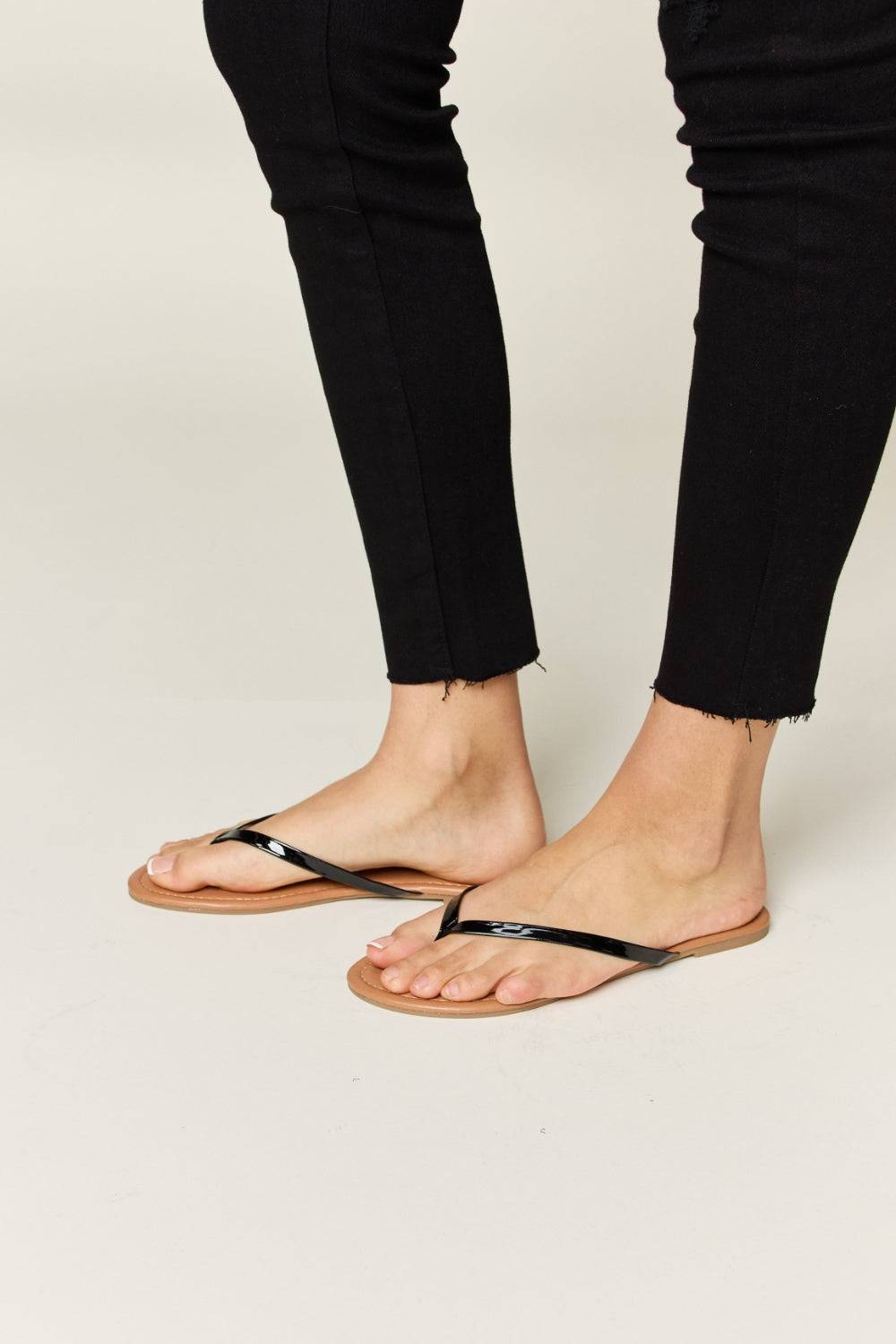 a woman standing on top of a pair of black sandals