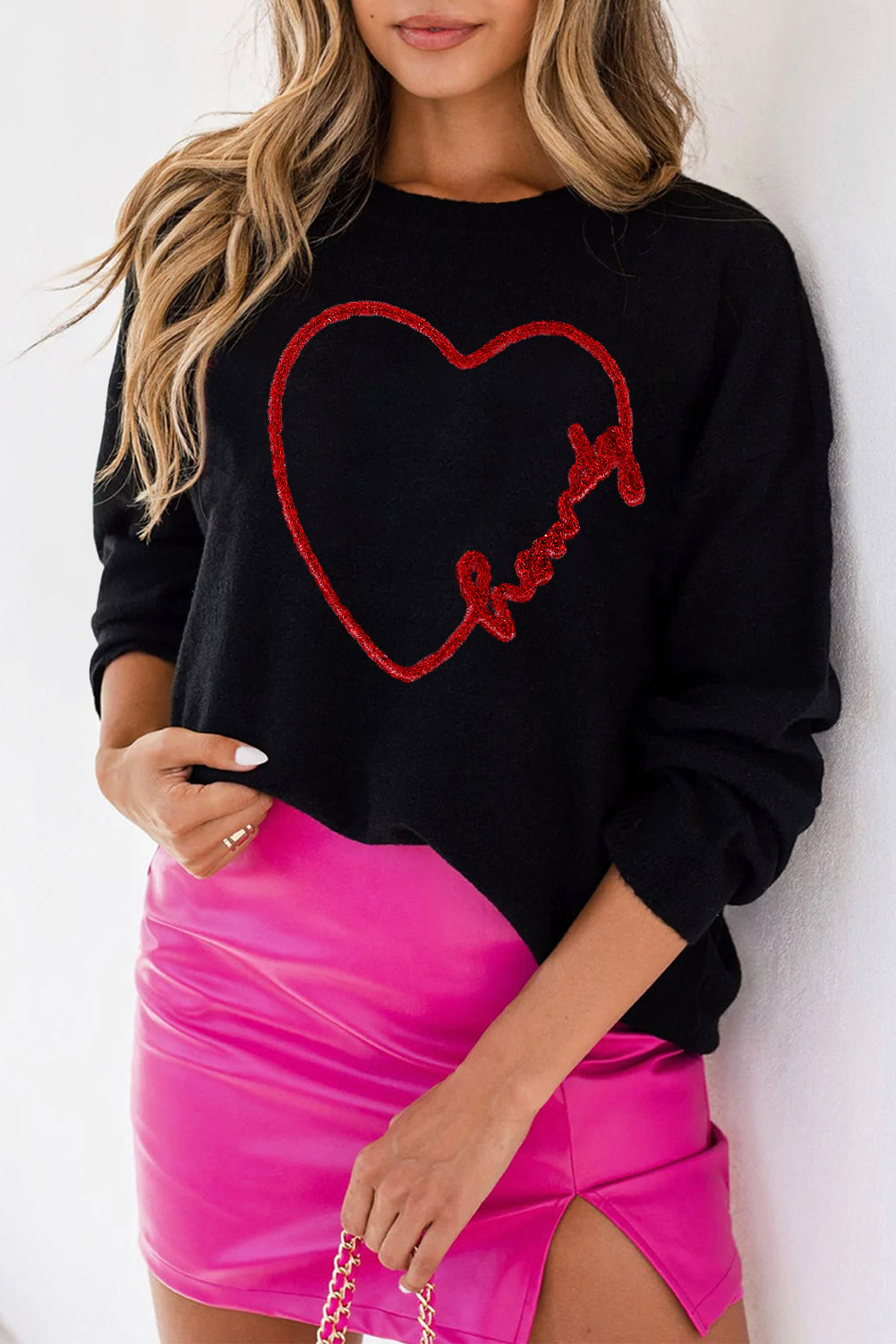 a woman wearing a black sweater with a heart drawn on it