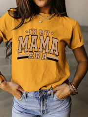 a woman wearing a yellow shirt that says in my mama era